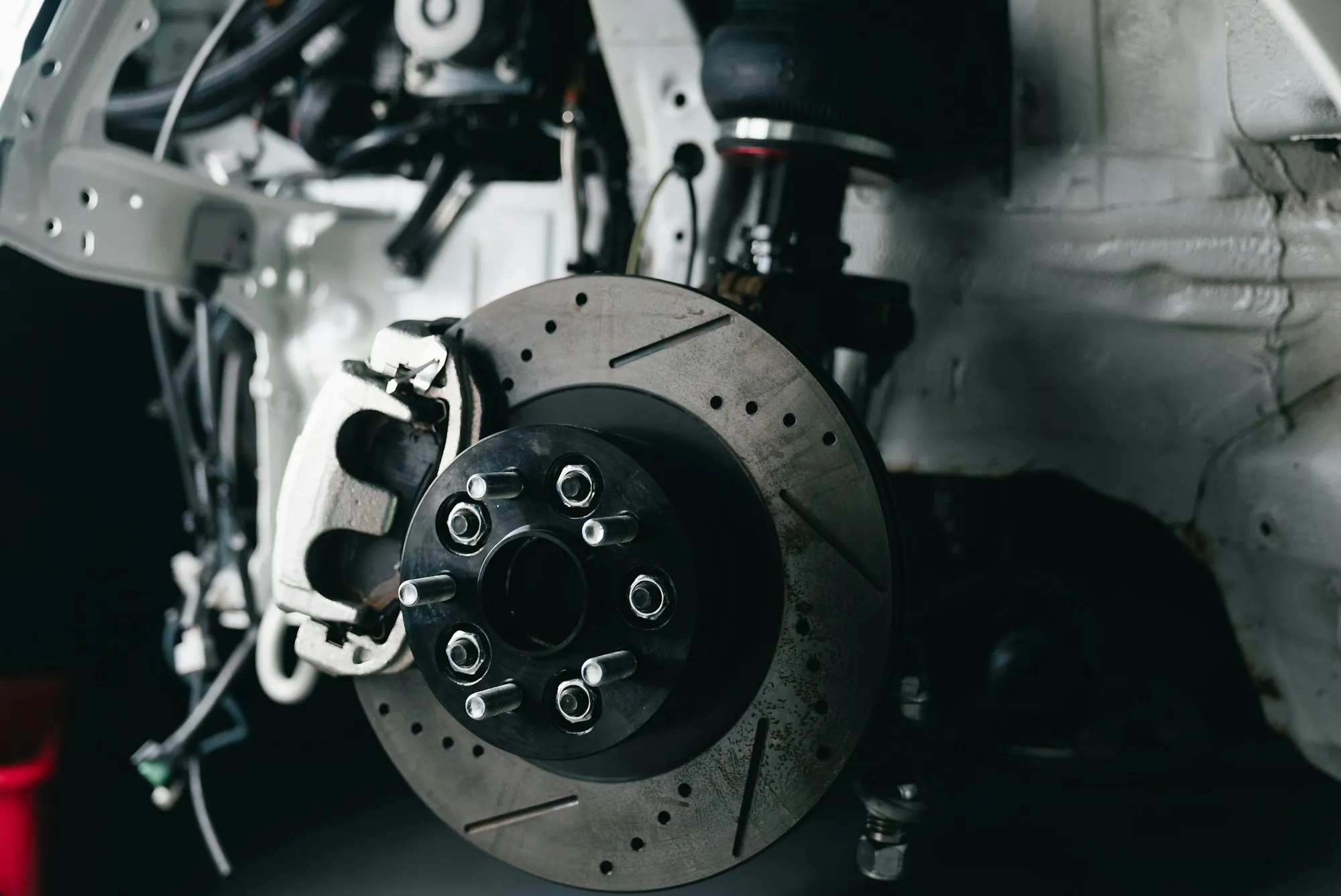Drilled brake rotor and caliper on a raised car