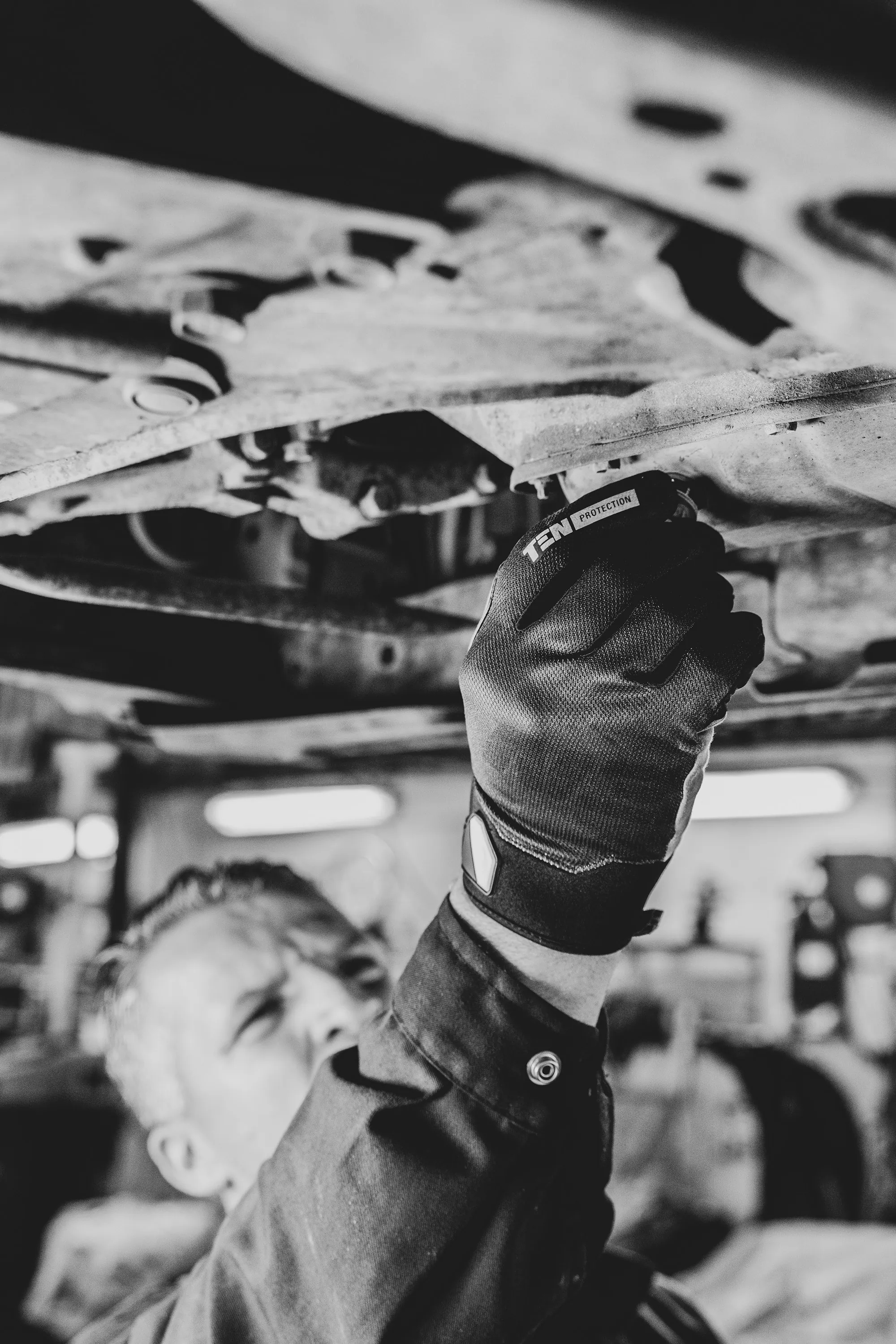 Mechanic in work clothes standing beside a vehicle in the shop