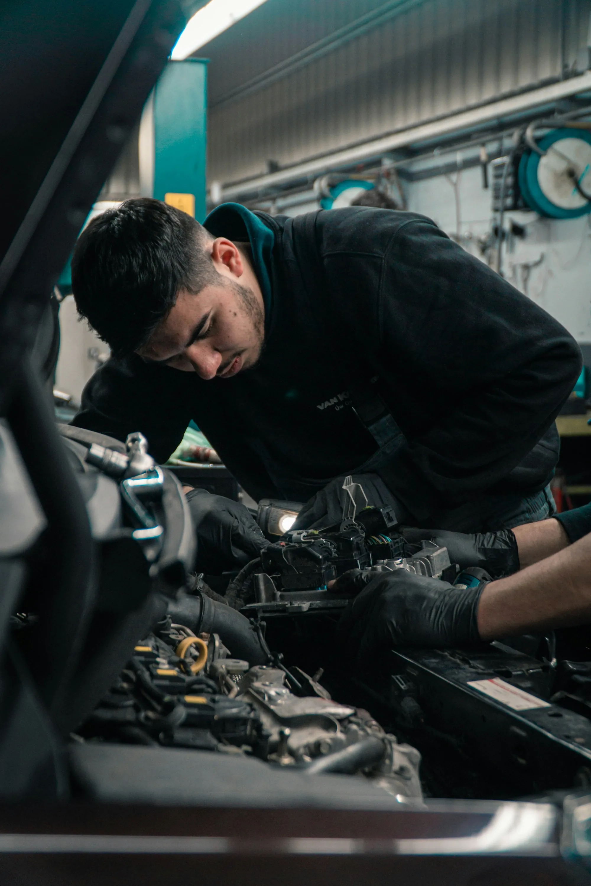 Mechanic leaning deep into an engine bay with a work light
