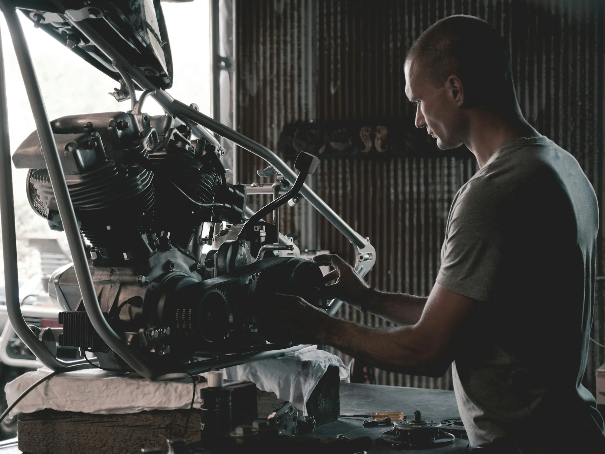 Mechanic in a t-shirt working on an engine fixed to a stand