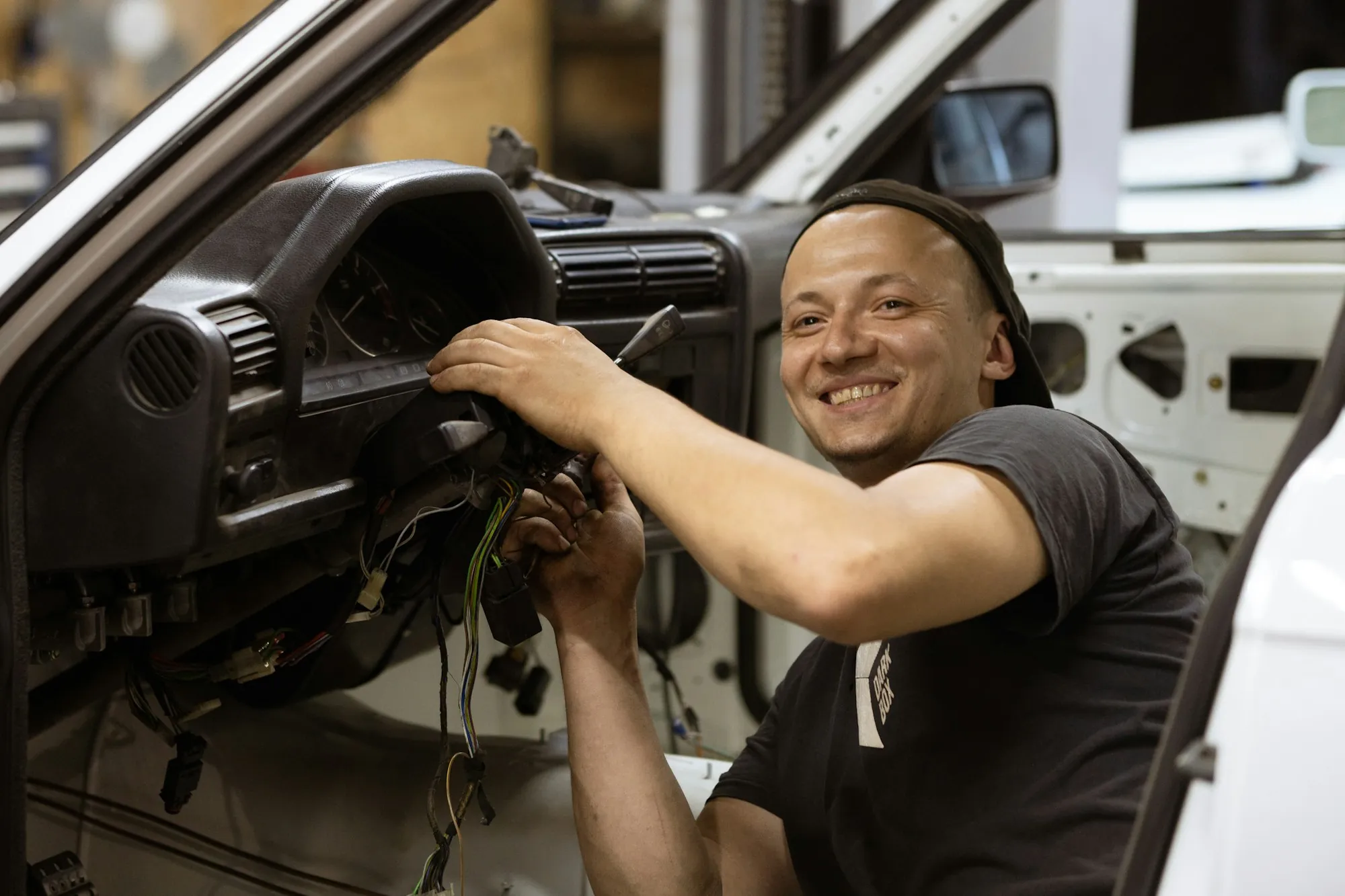 Mechanic smiling while working under the dashboard of a car